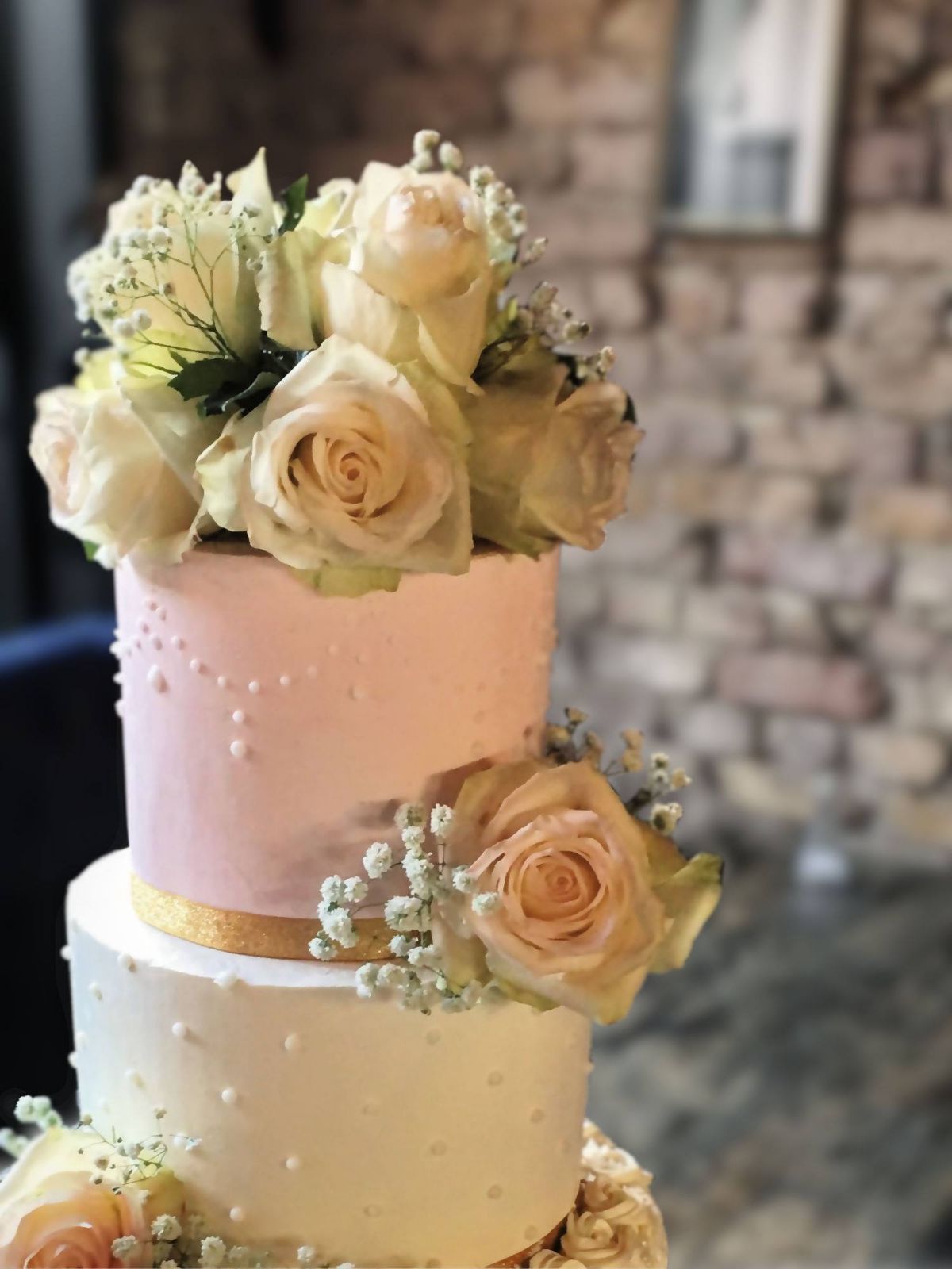 A 3 tier cake, covered with italian meringue buttercream, hand piped details and fresh roses.