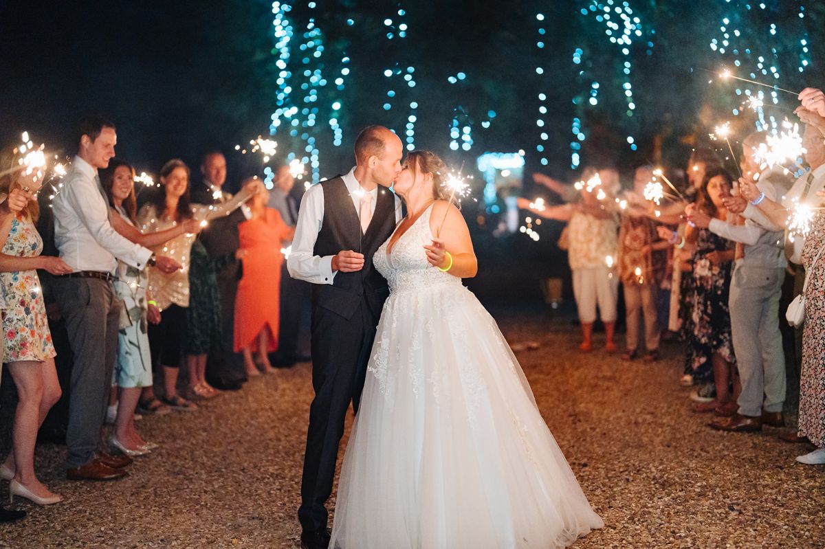 The newly weds kiss under the fairy lit tree