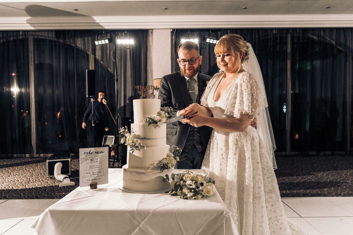 Cake cutting time as guests congratulate the happy couple at Jessica and Rhys wedding which was hosted at Lion Quays Resort in Shropshire.