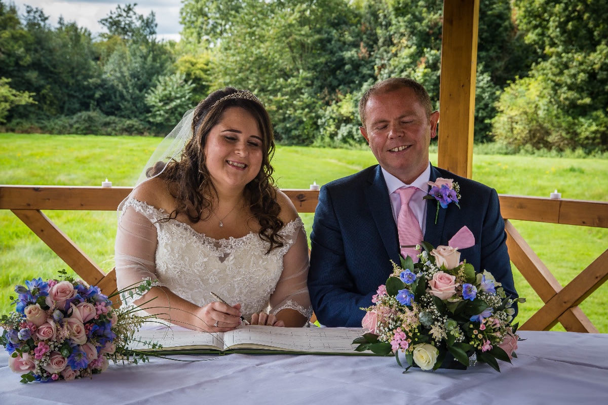 Jame and Lucy sign the register in the Wedding Pavilion at Grovefield House