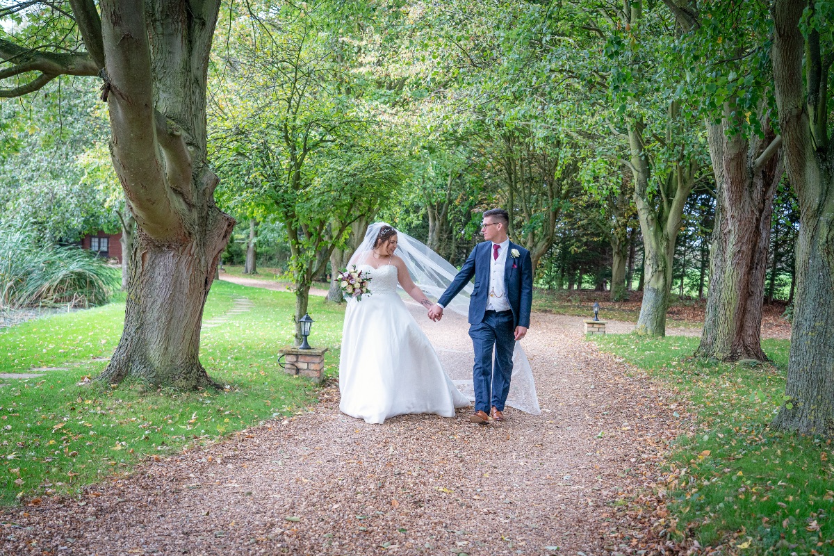 Bride and groom sheltered from the rain under a canopy of trees