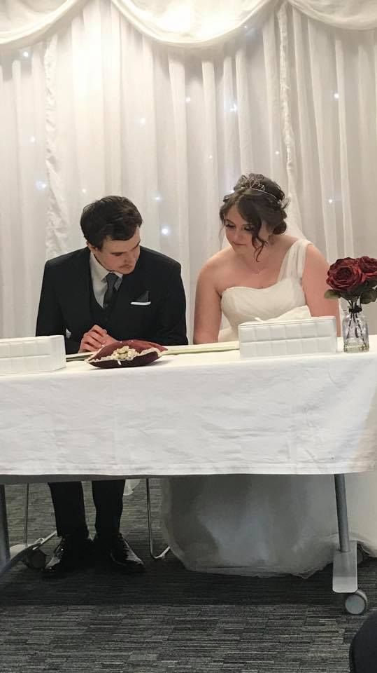 The bride and groom checking through the register before signing.