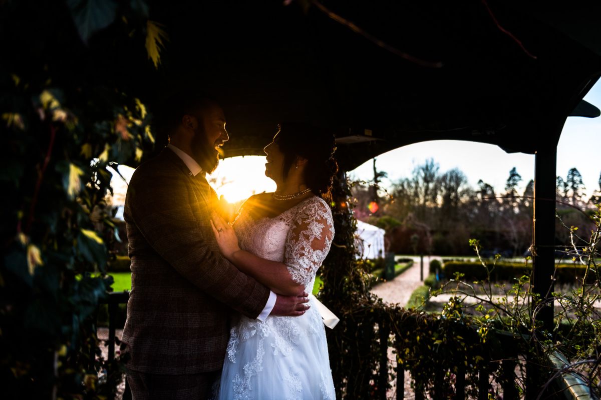 couple stand under the gazebo during a sunset at the golden hour at The Secret Gardens in Ashford