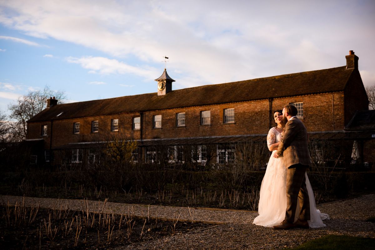 Couple stand in the sun during the golden hour in from of The Secret Gardens in Ashford