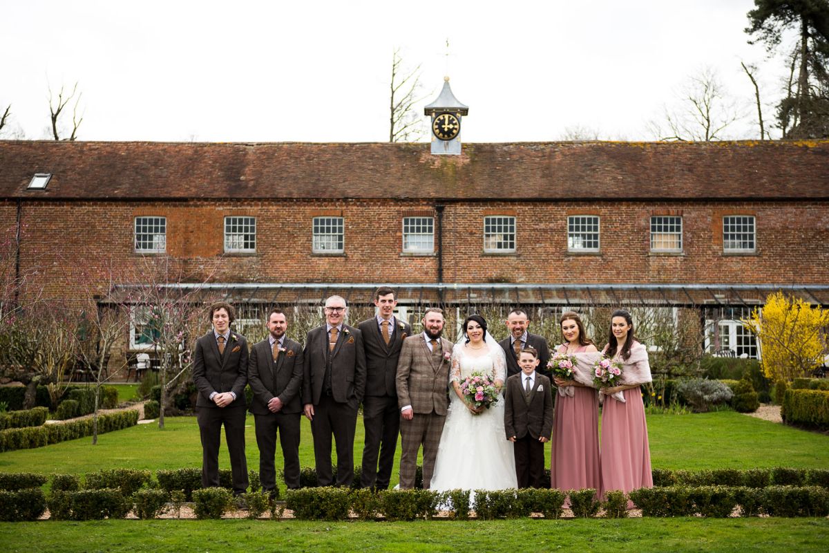 Bridesmaids and ushers line up with the bride and groom outsideThe Secret Gardens in Ashford