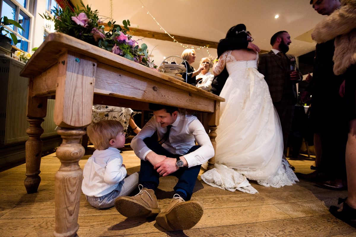 farther and son play hide and seek under a table at The Secret Gardens in Ashford