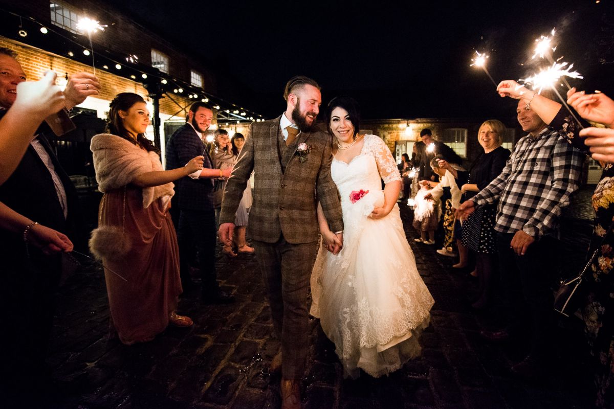 bride and groom walk down the aisle of sparklers at the end of a fantastic wedding day at The Secret Gardens in Ashford