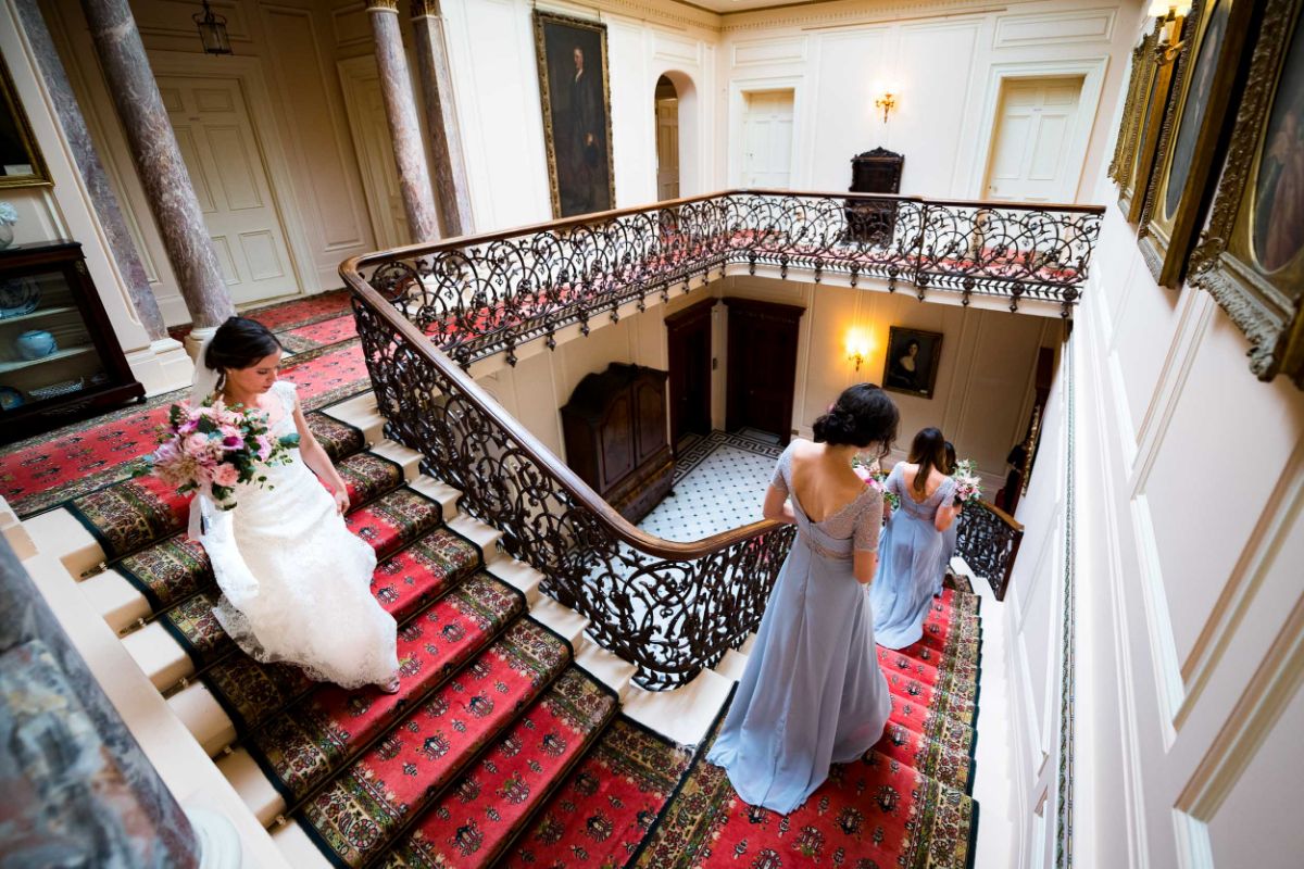 Bride and bride-maids walk down the stairs to the ceremony where her husband to be awaits at The Mount Ephraim Gardens