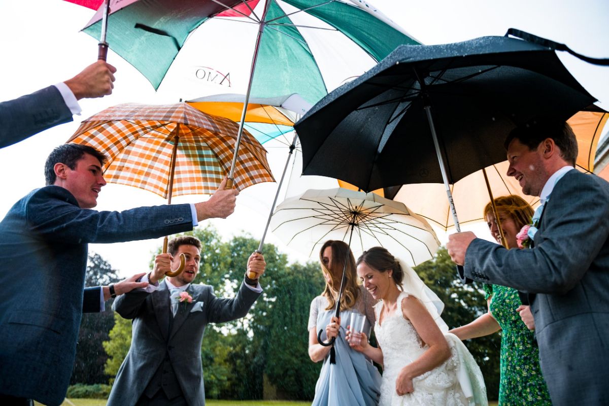The ushers line up with umbrellas to protect the bride from the down poor at The Mount Ephraim Gardens