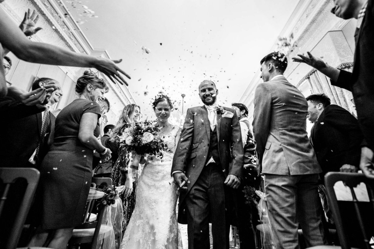 Bride and Groom walk down the aisle as confetti is being thrown at them at The Mount Ephraim Gardens