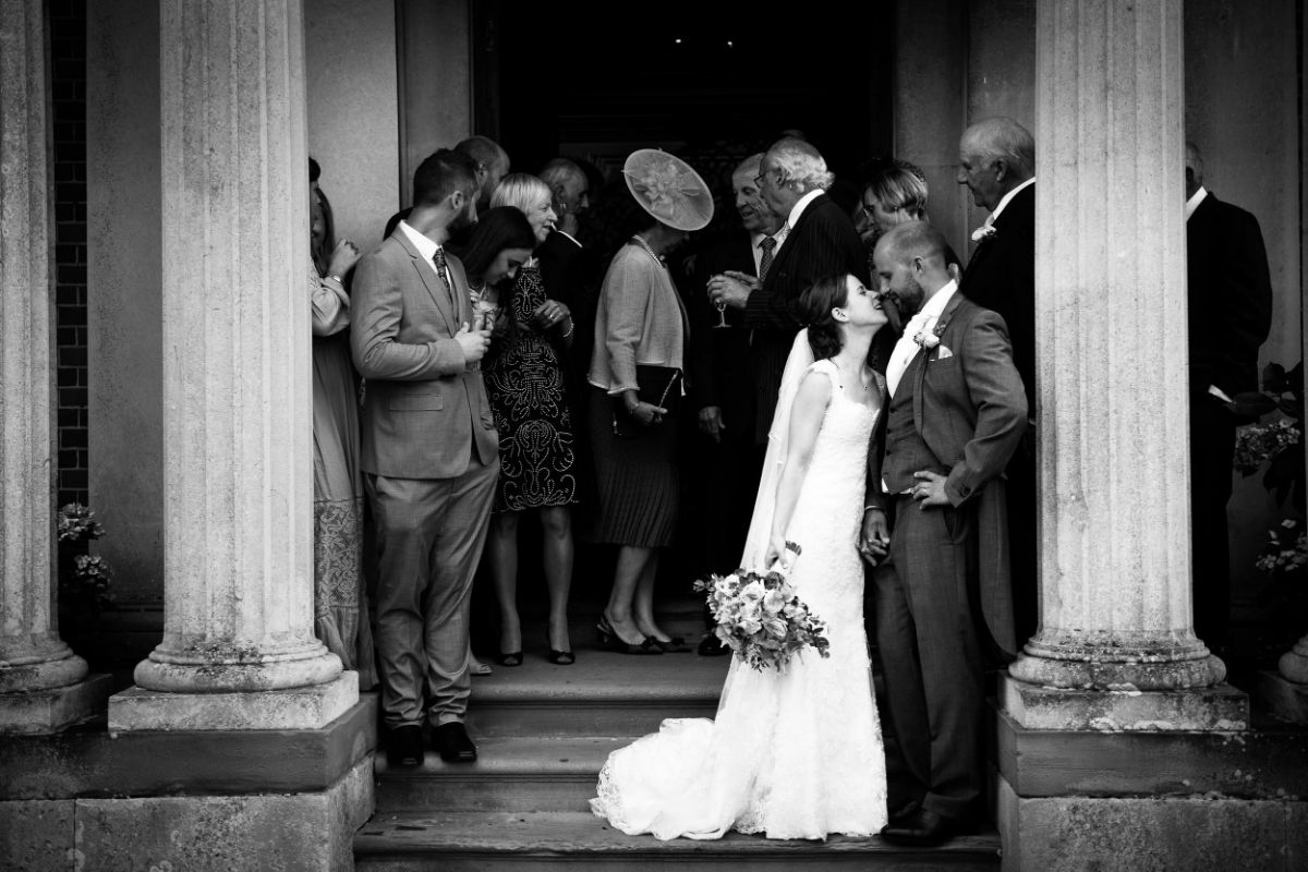 bride and groom share an intimate moment as everyone else is distracted on something behind them. The Mount Ephraim Gardens