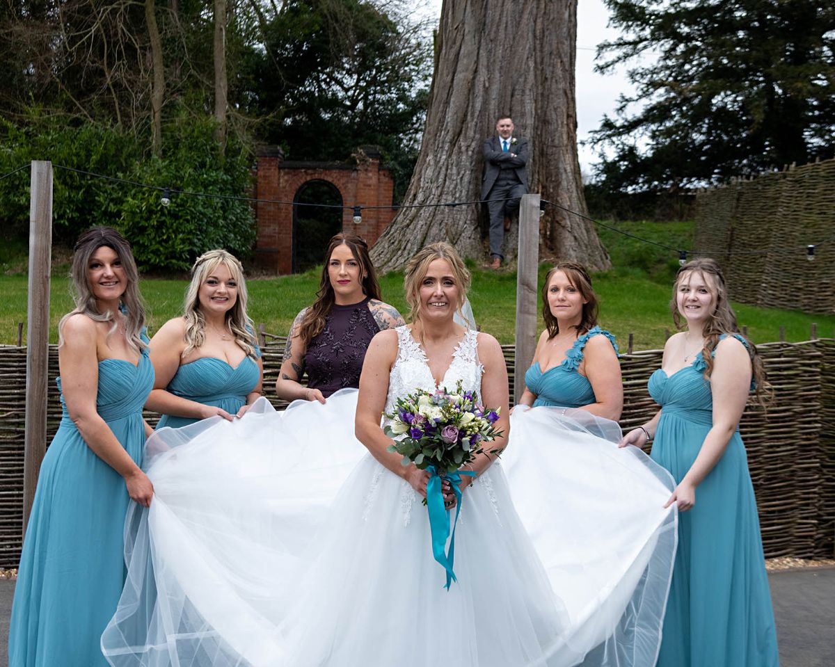A beautiful bride with her bridesmaids showing her wonderful wedding dress