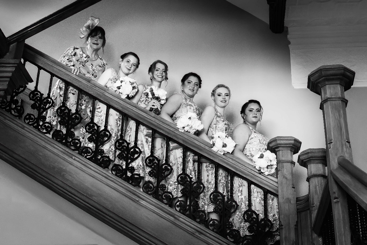 Bridesmaid descend the oak staircase prior to the ceremony