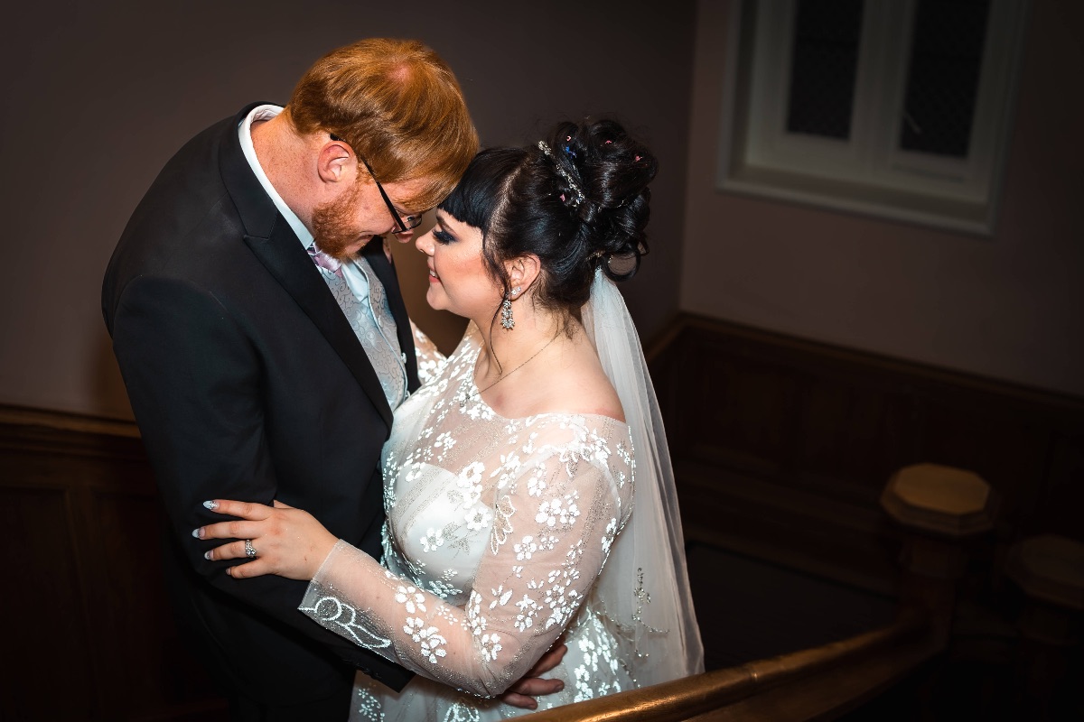 The bride & groom have portraits on the oak staircase