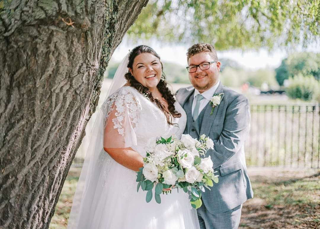 Beth & Tomasz standing by a tree