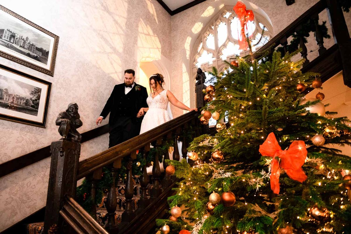 A Beautiful image of the couple coming down the grand Staircase with the Christmas tree