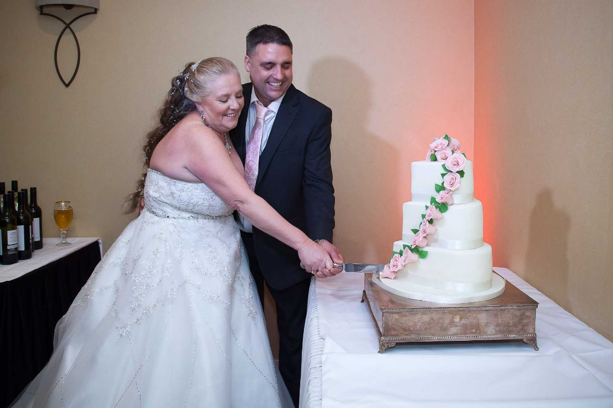The happy couple cutting the wedding cake.
