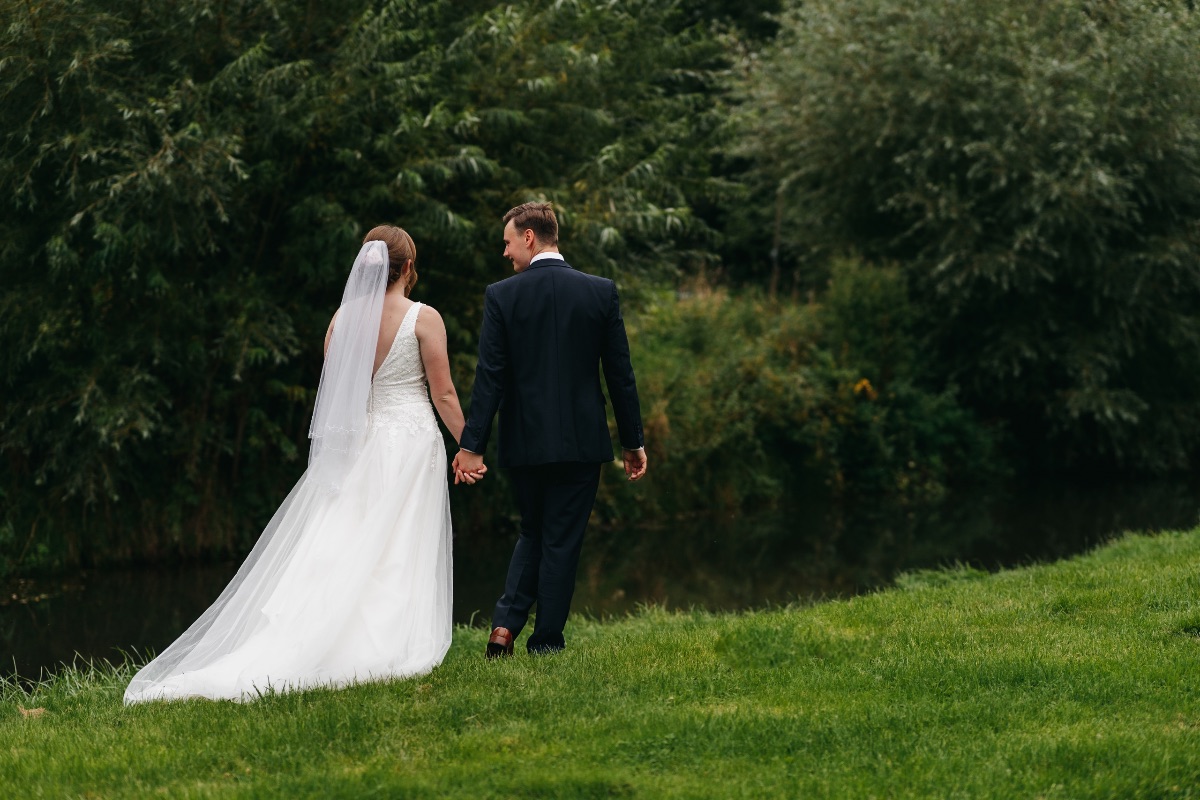 Bride and groom romantic photo walking next to the river at the venue