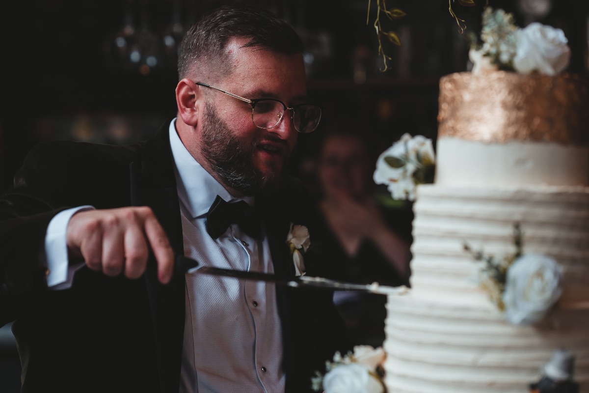Groom prepares to cut cake before sharing with his groom